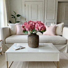 Load image into Gallery viewer, Field &amp; Rose pink artificial silk hydrangea stem, 53cm, in a rustic vase on a coffee table.
